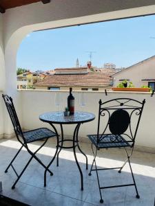 a table and two chairs with a bottle of wine on a balcony at Apartmani Ana Borovac in Funtana