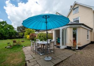 a patio with a table with a blue umbrella at 2 The Old Vicarage in Wangford