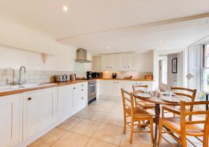 a kitchen with white cabinets and a table and chairs at 2 The Old Vicarage in Wangford