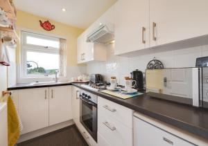 a kitchen with white cabinets and a stove top oven at Forget-me-not Bungalow in Seaton