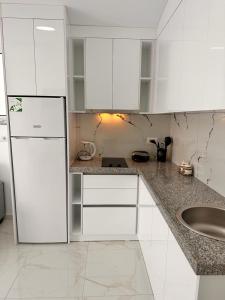 eine weiße Küche mit einer Spüle und einem Kühlschrank in der Unterkunft Vila SUN 2E in Ksamil