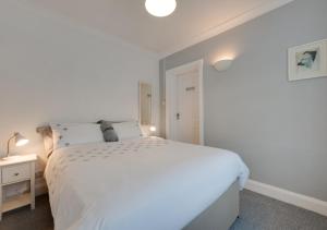 a white bedroom with a white bed and a night stand at Little Hollies in Salcombe Regis