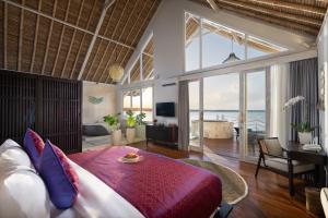 a bedroom with a large bed and a living room at Pramana Natura Nusa Penida in Nusa Penida