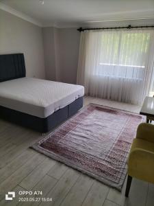 a bedroom with a bed and a window and a rug at TRABZON-AKÇAABAT/MERSİN in Vartara