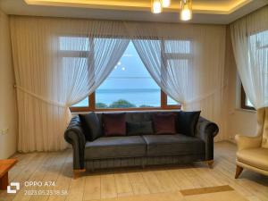 a living room with a couch in front of a window at TRABZON-AKÇAABAT/MERSİN in Vartara