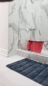 baño con alfombra azul y cubo rojo en An Ideal Apartment for you. en Brampton