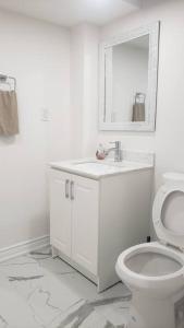 a white bathroom with a toilet and a mirror at An Ideal Apartment for you. in Brampton