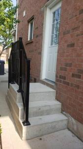 a brick building with a staircase leading to a white door at An Ideal Apartment for you. in Brampton