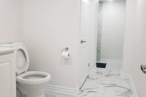 a white bathroom with a toilet and toilet paper on the floor at An Ideal Apartment for you. in Brampton