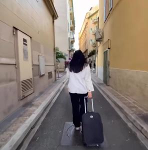 a woman walking down a street with a suitcase at Open House #hostel in Nice