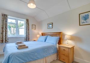 a bedroom with a bed with blue sheets and a window at The Malt House in Colyton