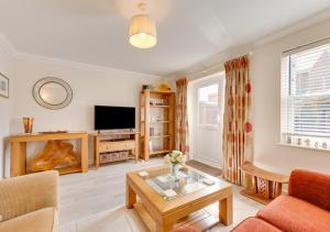 uma sala de estar com um sofá e uma televisão em Tucked Away Cottage em Seaton
