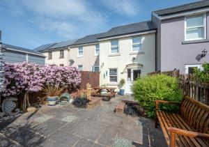 a backyard with a wooden bench and a house at Tucked Away Cottage in Seaton