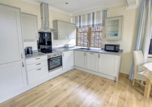 a kitchen with white cabinets and a wooden floor at Sovereign in Seaton