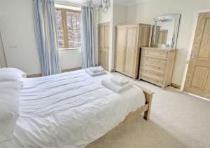 - une chambre avec un grand lit blanc et une commode dans l'établissement Sovereign, à Seaton