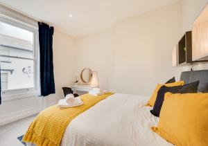 a bedroom with a bed with a yellow blanket and a window at The Old Drapers House in Brixham
