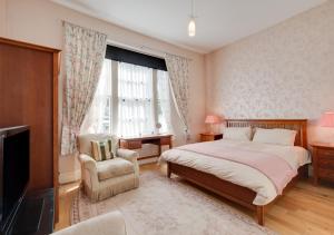 a bedroom with a bed and a chair and a window at Rutland Lodge Wellswood Mews in Torquay