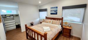 ein Schlafzimmer mit einem großen Bett und zwei Fenstern in der Unterkunft Beach Getaway - Blessington Villa in South Arm
