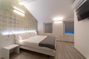 a bedroom with a white bed and a television at CityU - Grazioli 27 Trento Centro con parcheggio privato in Trento