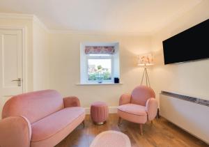 salon z różowymi krzesłami i telewizorem z płaskim ekranem w obiekcie Honey Cottage Mews w mieście Torquay
