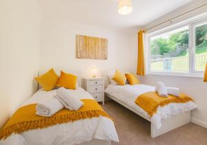 2 camas en un dormitorio con ventana en Crows Nest en Brixham