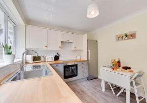 una cocina con armarios blancos y fregadero en Crows Nest en Brixham