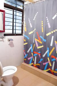 a bathroom with a shower curtain and a toilet at Coorg Nature Breeze Homestay in Madikeri