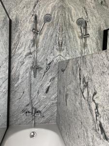 a shower in a bathroom with a marble wall at Hotel "Senleja" in Sigulda