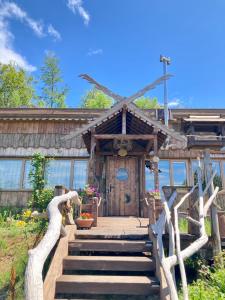 ein Holzhaus mit einer Treppe, die zu einem Gebäude führt in der Unterkunft Tezukuri Cottage Mauranarani - Vacation STAY 49824v in Shimatokkari