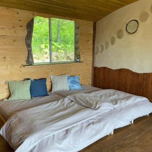 1 cama grande en una cabaña de madera con ventana en Tezukuri Cottage Mauranarani - Vacation STAY 49824v, en Shimatokkari