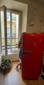 ニースにあるOpen House #hostelの赤い冷蔵庫の横に女性が立っている