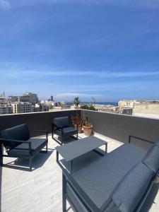 a patio with couches and tables on a roof at Sliema Distant Seaview Penthouse in Sliema