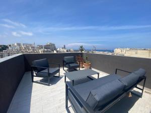 a balcony with chairs and a table on a roof at Sliema Distant Seaview Penthouse in Sliema
