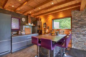 a kitchen with purple chairs and a wooden ceiling at chalet la traverse in Allemont