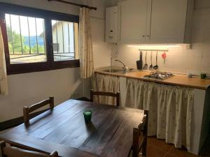 cocina con mesa de madera y cocina con fregadero en LA MINA Alojamiento en plena naturaleza en Garganta de los Montes