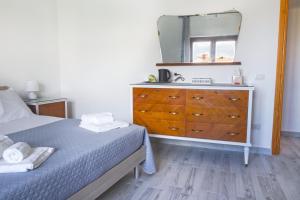 ein Schlafzimmer mit einem Bett und eine Kommode mit einem Spiegel in der Unterkunft Mencin in Carloforte