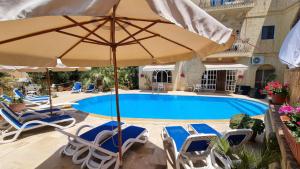 a swimming pool with chairs and an umbrella at Villa Serenity B&B in Sannat