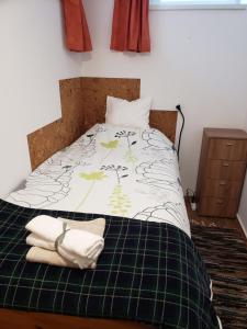 a bed with a green and white comforter with towels on it at Berkenye Pihenőház in Sárvár