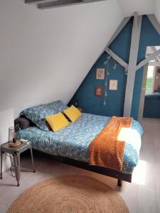 um quarto com uma cama com uma parede azul em Le grenier de Mamou em Hesdigneul-lès-Boulogne