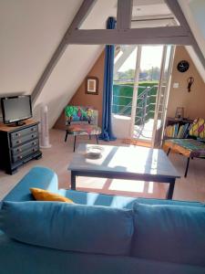 ein Wohnzimmer mit einem blauen Sofa und einem Tisch in der Unterkunft Le grenier de Mamou in Hesdigneul-lès-Boulogne