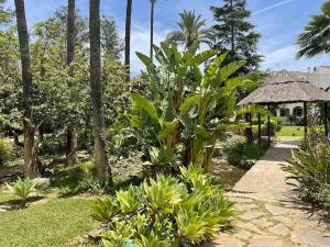 einen Garten mit Palmen und einem Weg in der Unterkunft Casa Sally - Mijas Golf in Mijas Costa