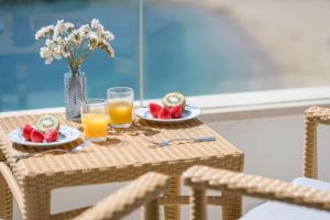 une table avec deux assiettes de fruits et de jus d'orange dans l'établissement Hotel Rosamar, à Sant Antoni de Calonge