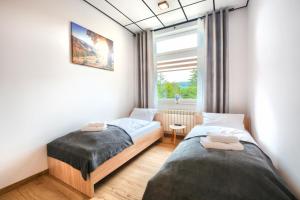 2 camas en una habitación pequeña con ventana en Apartamenty w Bieszczadzkim Horyzoncie, en Ustrzyki Dolne