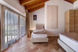 Schlafzimmer mit einem Bett und großen Fenstern in der Unterkunft Casale la Coccinella Gelsomino in Caprino Veronese
