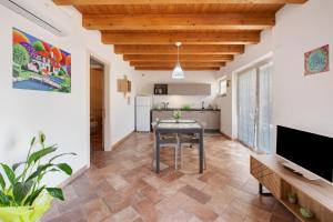 eine Küche und ein Wohnzimmer mit einem Tisch und einem TV in der Unterkunft Casale la Coccinella Gelsomino in Caprino Veronese