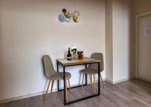 a table with three chairs next to a wall at Vila Bor apartmani in Bečej