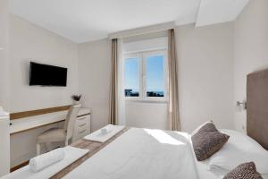 Habitación blanca con cama, escritorio y ventana en Apartment Hrvoje -nur 50m bis zum Meer, en Promajna