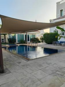 a swimming pool with an umbrella on a patio at Villa 29 Suite A - Home Vacation in Dubai