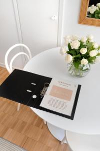 einem weißen Tisch mit einer Vase weißer Rosen darauf in der Unterkunft Stylish Nordic Studio by Tram Stop in Helsinki