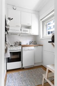 a white kitchen with white appliances and a window at Stylish Nordic Studio by Tram Stop in Helsinki